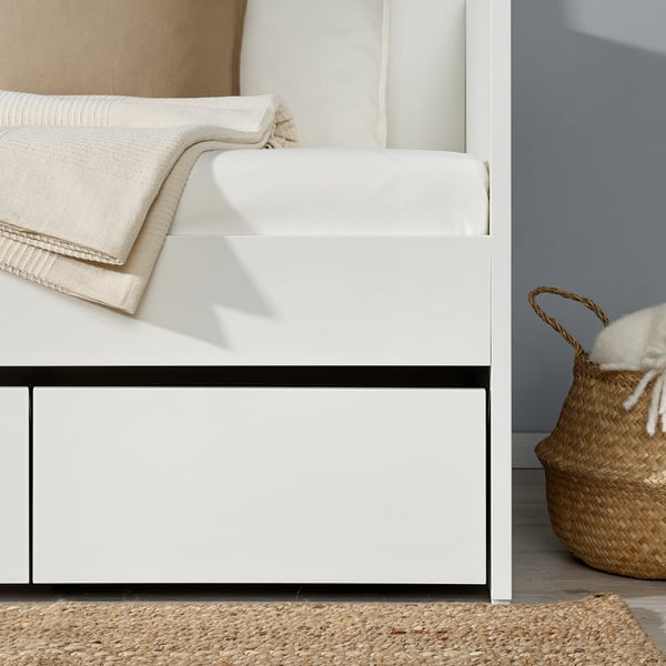 A white daybed with built-in storage drawers, featuring a clean design and cushions neatly arranged.