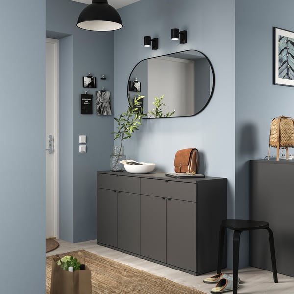 Modern hall with VIHALS sideboard, mirror, and decor. Dark grey sideboard fits under a large mirror, featuring a blend of drawers and shelves.