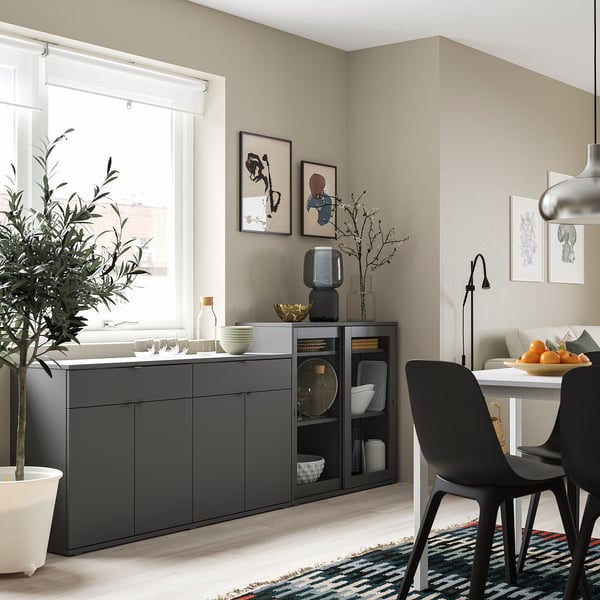 Modern dining room with grey cabinet and black chairs, colourful rug, and wall art.