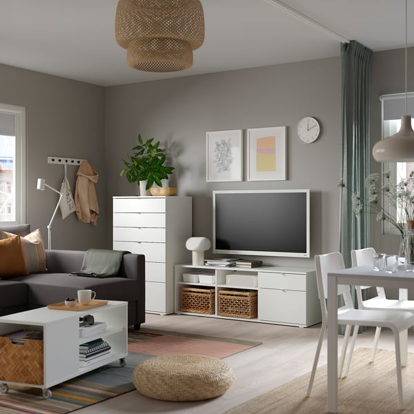 Modern living room with grey walls, a grey sofa, white tv stand, and a flat-screen tv. Decorated with plants, art, and natural textiles.