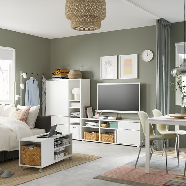 Modern living room with green walls, featuring a white VIHALS tv stand, a cosy bed, and a round rug.