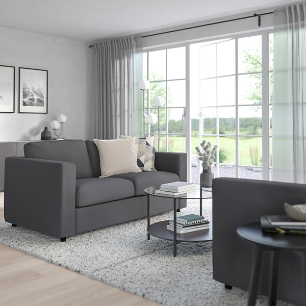 Modern living room with grey VIMLE sofa, cotton blend cushions, patterned rug, and large windows with sheer curtains.