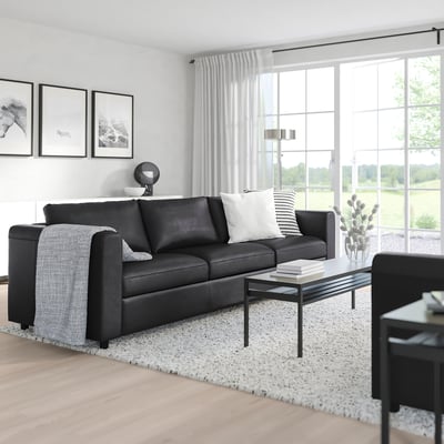 Modern living room with large VIMLE black sofa, white rug, coffee table, and large window.