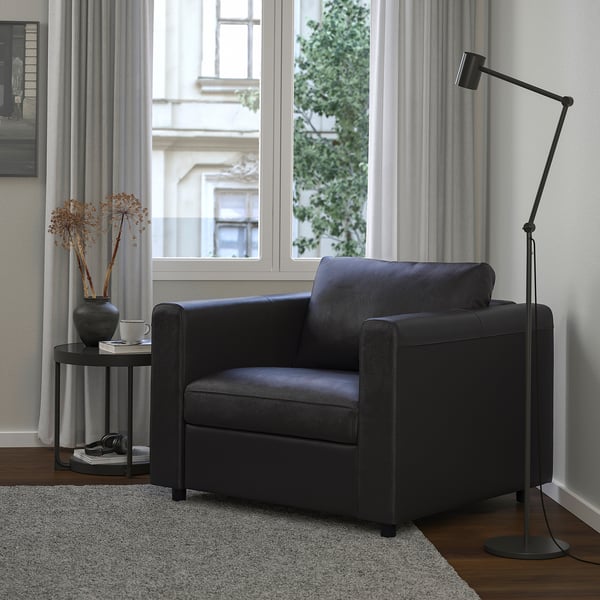 Black VIMLE armchair in modern living room with floor lamp and table decor.
