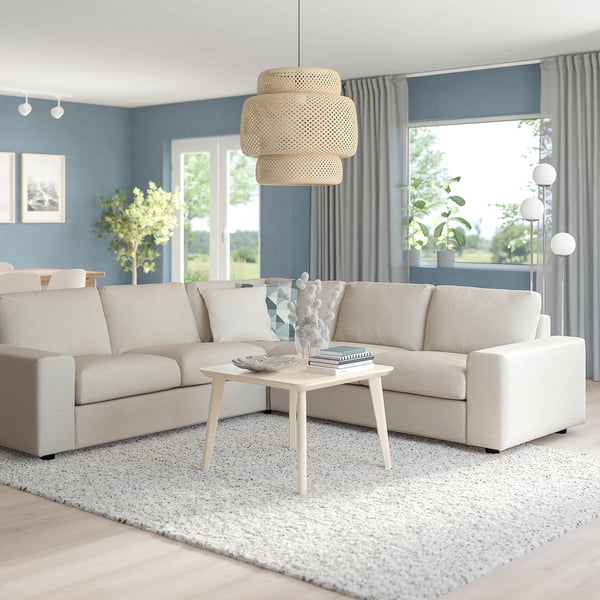 Modern living room with large beige VIMLE sectional sofa, wooden coffee table, unique hanging lamp, and windows showing greenery.
