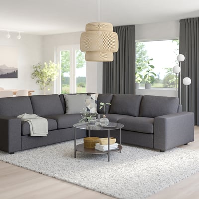 Modern living room with grey VIMLE sectional sofa, wooden coffee table, white rug, large window, and unique pendant light.