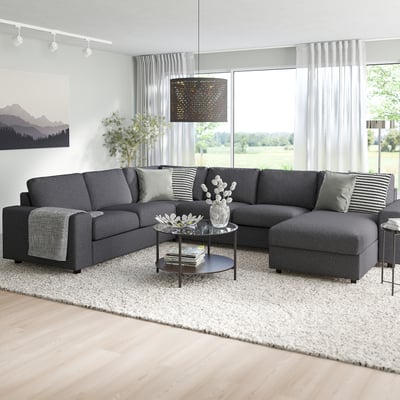Grey l-shape VIMLE sofa, large cushions, white rug, glass table, big windows.