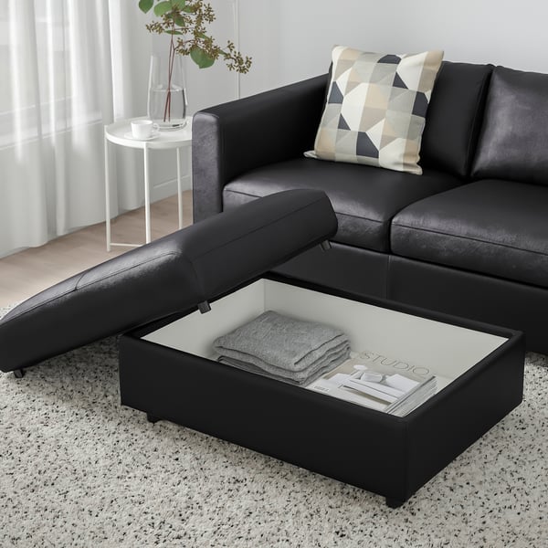 Modern living room with black VIMLE sofa featuring a lift-top coffee table with storage, revealing folded blankets and a magazine.