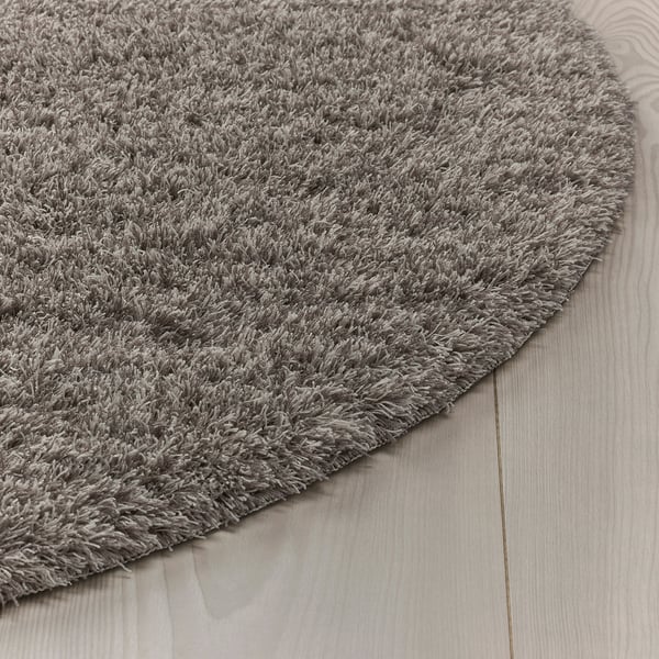 Fluffy grey rug with anti-slip backing on wooden floor.