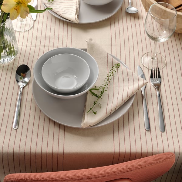 Table set with white dishes, silverware, and striped tablecloth, featuring green garnish on napkins.