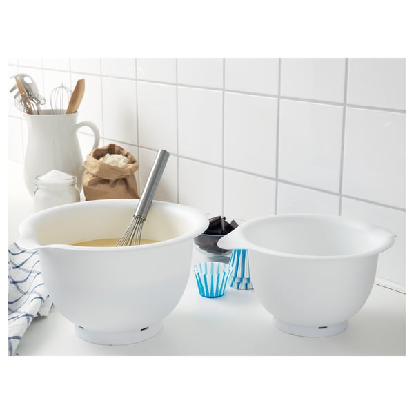 Two white mixing bowls on a countertop; one contains batter and a whisk. The bowls have non-slip bases for stability.