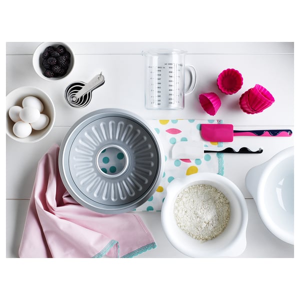 Baking scene with VISPAD grey bowl, pink spatula, ingredients, measuring tools on polka dotted cloth.