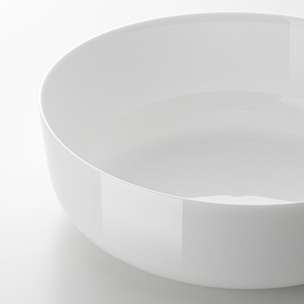 White, glossy bowl, likely glass, on plain surface.