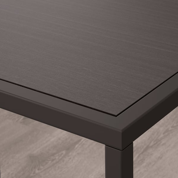 Close-up of modern table with sleek black top and sturdy, minimalist legs.