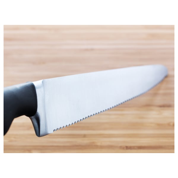 Knife with serrated edge on wooden surface. High-quality blade, crafted from stainless steel, designed for durability and sharpness.