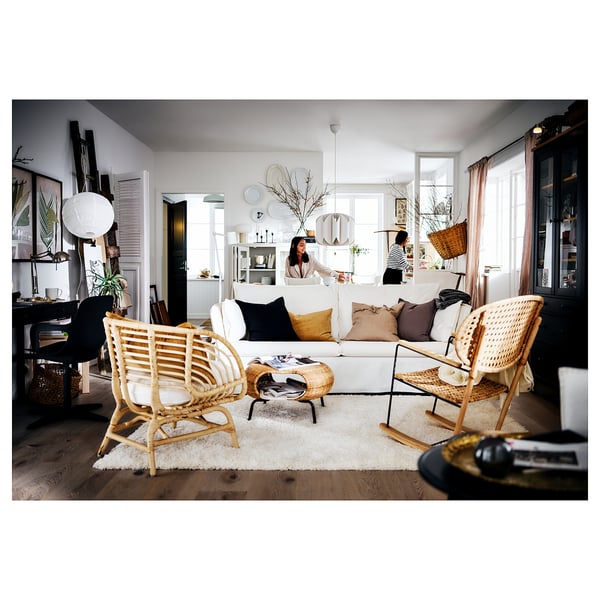 Spacious living room with white shaggy rug, white couch, wicker chairs, and plants.