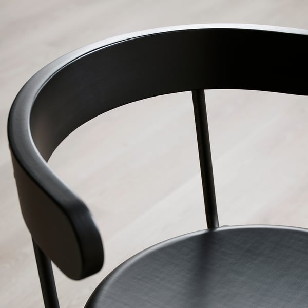 Black modern chair with rounded backrest and armrest. Sleek, polished design.