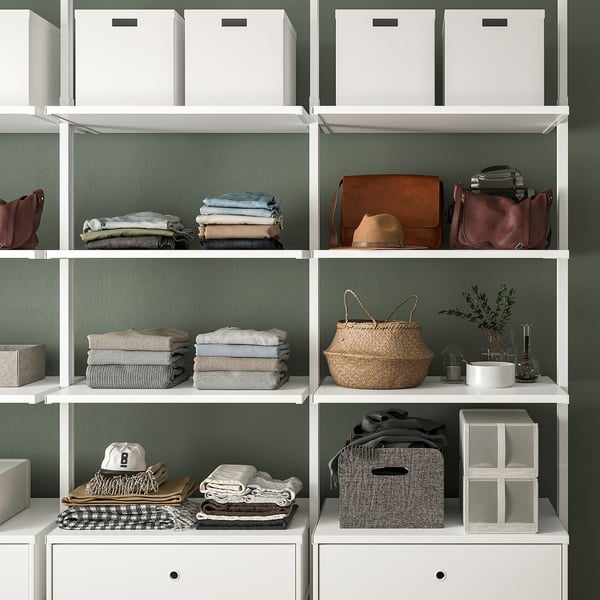 Plauktu bloks ar kārtīgi salocītām drēbēm, rokassomām un uzglabāšanas kastēm, kas demonstrē organizētu uzglabāšanu.