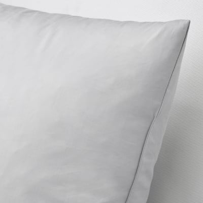 Mīksts, dūnu pildīts spilvens ar kokvilnas pārvalku, kas parāda tā plīša tekstūru un kvalitāti.