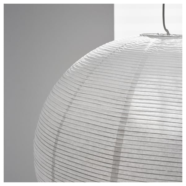 Melnbalts tuvplāns ar piekaramu rīsu papīra lampu ar vertikālām līnijām, kas parāda tās teksturēto, roku darbu kvalitāti un smalko gaismas izkliedi.
