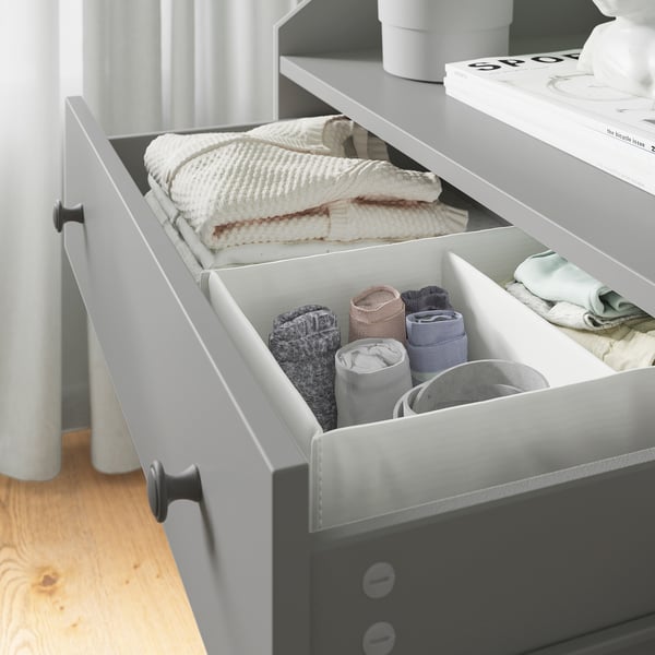 Organizēta kumode ar kārtīgi salocītām drēbēm mūsdienīgā guļamistabā.