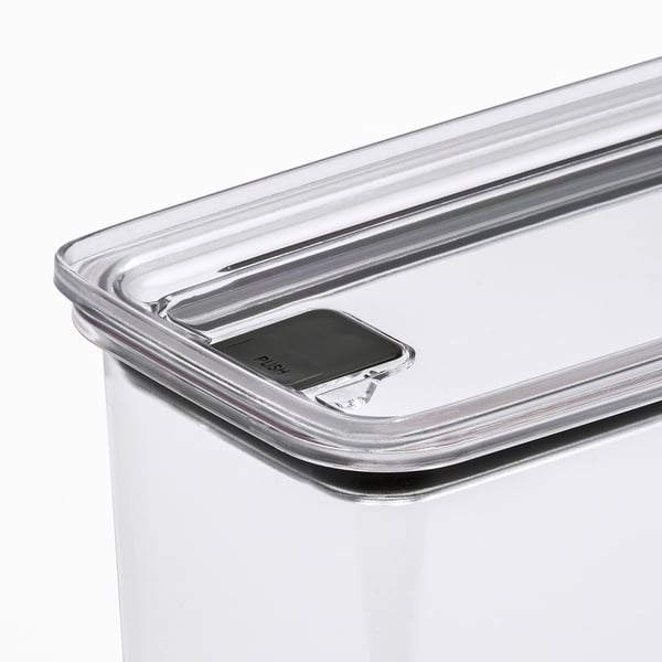 Caurspīdīgas plastmasas pārtikas trauka tuvplāns ar drošu vāku ar spiedpogu.