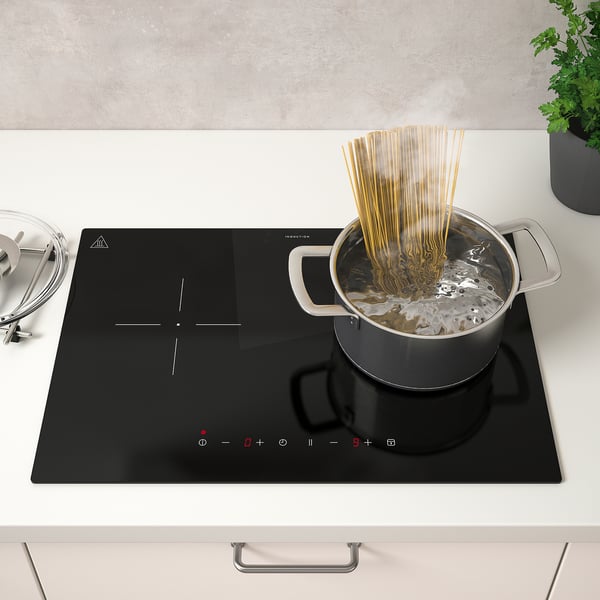 Spageti gatavošana uz modernas indukcijas plīts ar digitālajām vadības ierīcēm.
