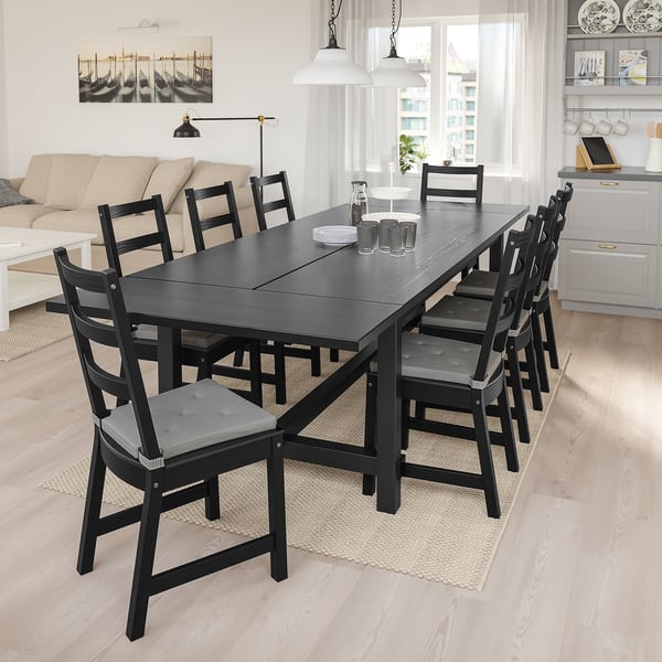 Mūsdienīgs ēdamistabas komplekts ar melnu NORDVIKEN galdu un 8 krēsliem gaišā dzīvojamā telpā.