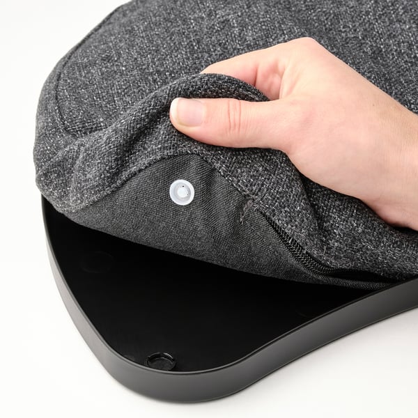 Roku pacelšanas melns klēpjdatora spilvens ar auduma pārvalku virs līdzenas virsmas.