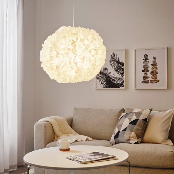 Mājīga dzīvojamā istaba ar lielu VINDKAST piekaramo lampu, dīvānu un mākslas darbiem.