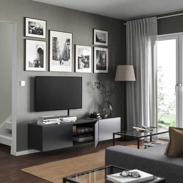 Современная гостиная с черно-белым декором, телевизором на скамейке BESTÅ, фотографиями, вазой, стеклянным столом.