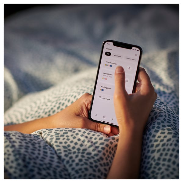 Человек, держащий смартфон с приложением ikea для умного дома. Или смартфон с приложением ikea home.