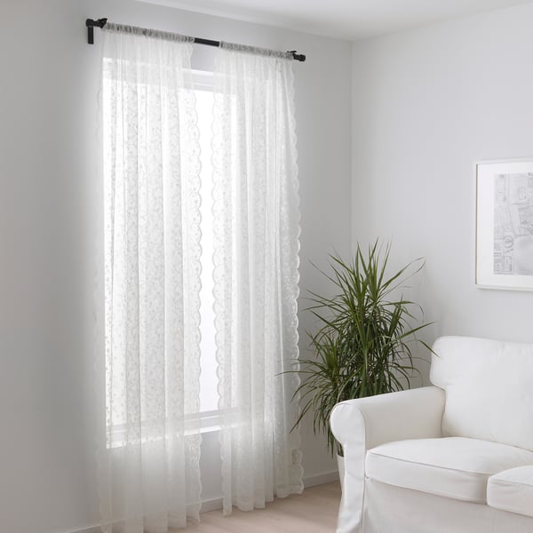 Прозрачные шторы пропускают свет в минималистичную комнату со стулом и растением.