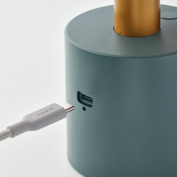 Зеленая портативная лампа с портом зарядки usb-c, показывающая подключенный фиолетовый кабель usb-c.