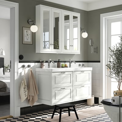 Современный туалетный столик в ванной комнате с двойной раковиной белого цвета с зеркальным шкафом, черно-белым шахматным полом, зеленой стеной и подвесными полотенцами.