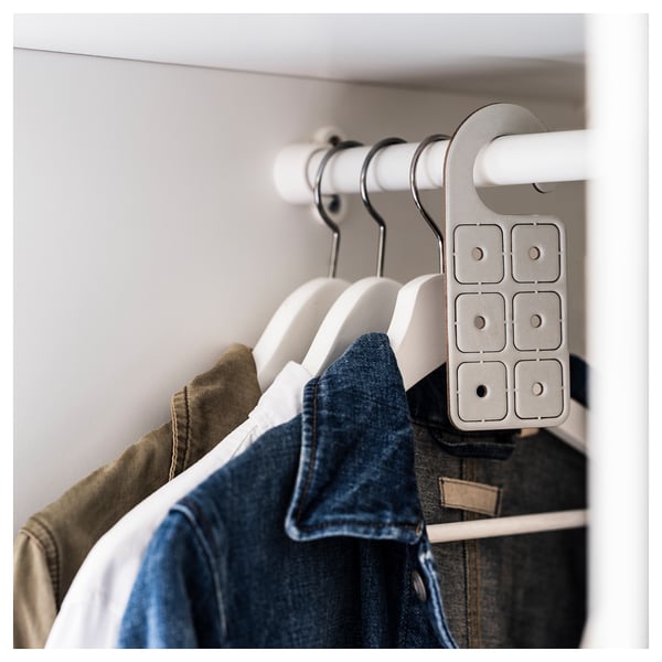 Clothes hangers with garments in closet, grey hanger attached.