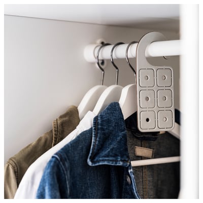 Clothes hangers with garments in closet, grey hanger attached.