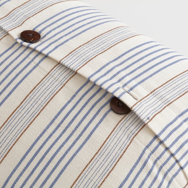 Close-up of striped cushion cover with button closure.