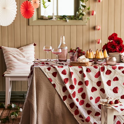 Elegant table set with ANLEDNING red-patterned glassware, pink cushions, strawberries, and red flowers for festive decor.