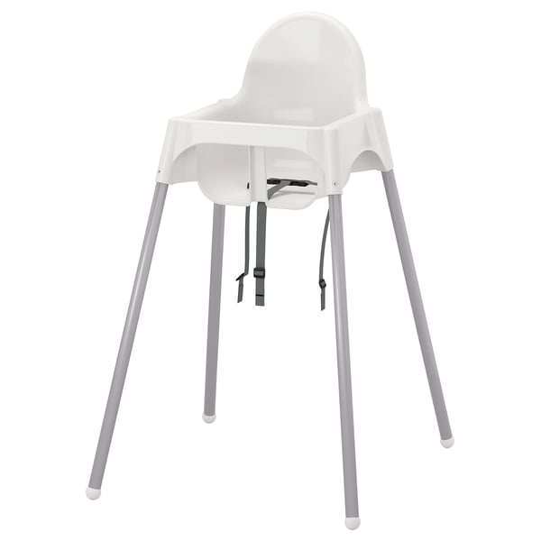 A white ikea ANTILOP high chair with grey legs and black straps for securing a child.
