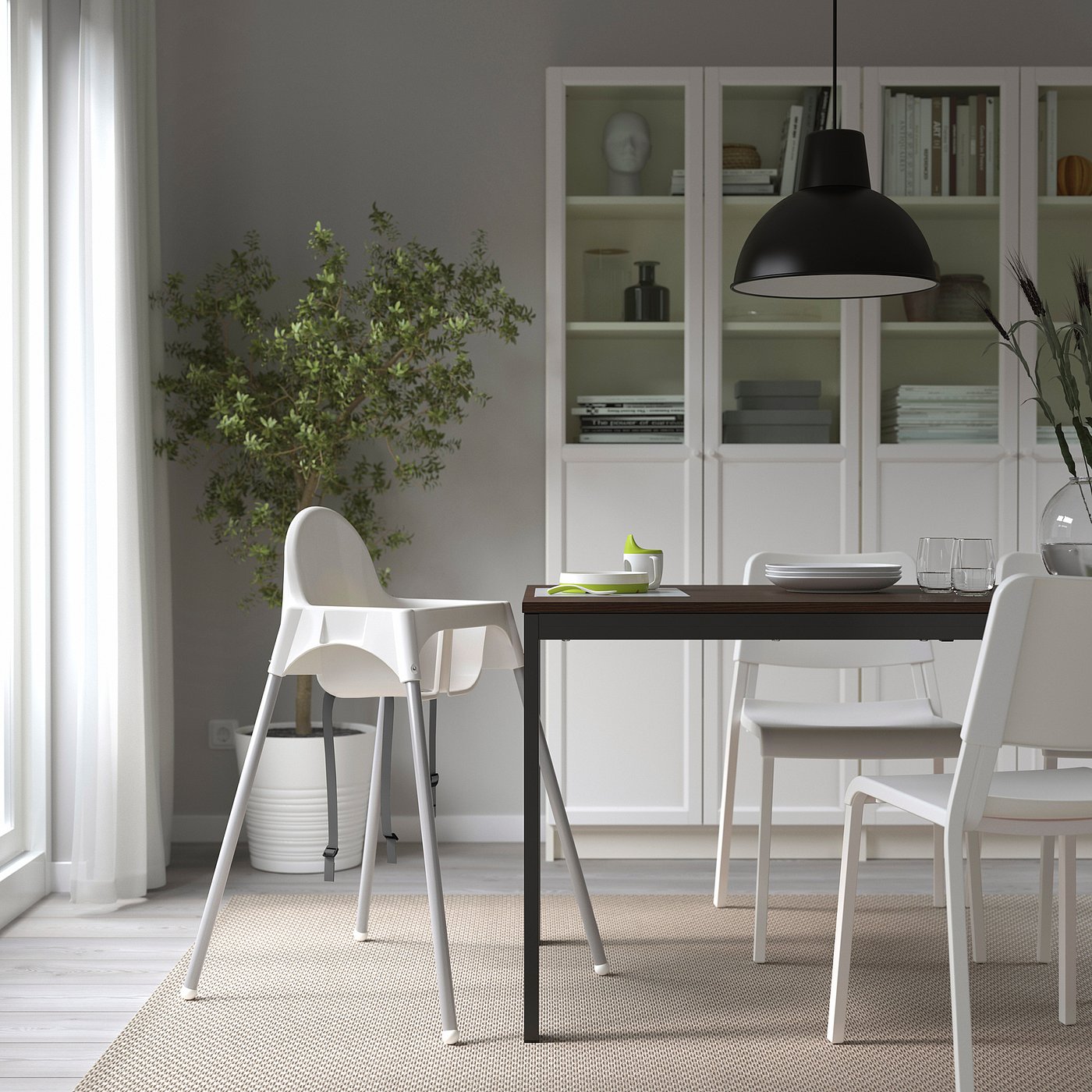 Modern dining room with ANTILOP highchair, white table and chairs, houseplant, and bookshelf.