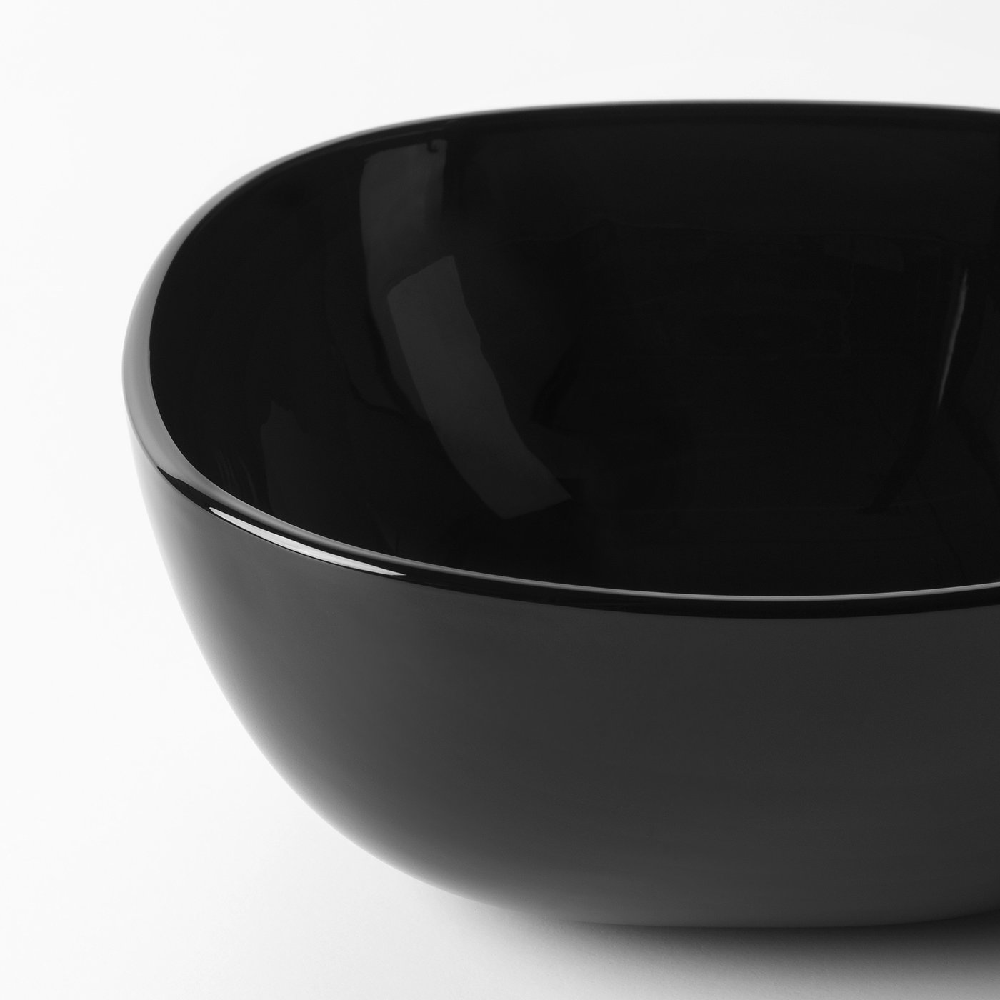 Close-up of sleek black glossy bowl. Shiny, smooth surface. Square shape.