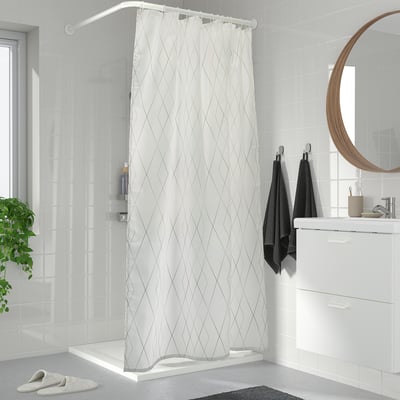 Modern bathroom with grey-white diamond shower curtain, large walk-in shower, white cabinet, mirror, plant.