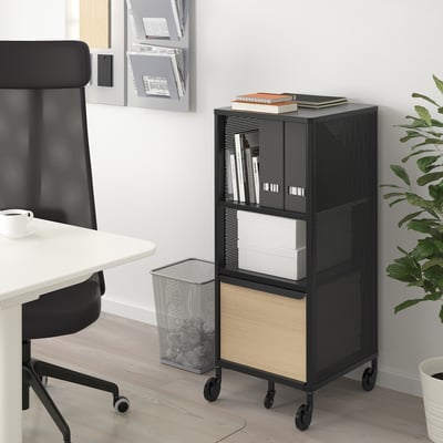 Black BEKANT storage unit at office desk with shelves, drawers, chair, and plant.