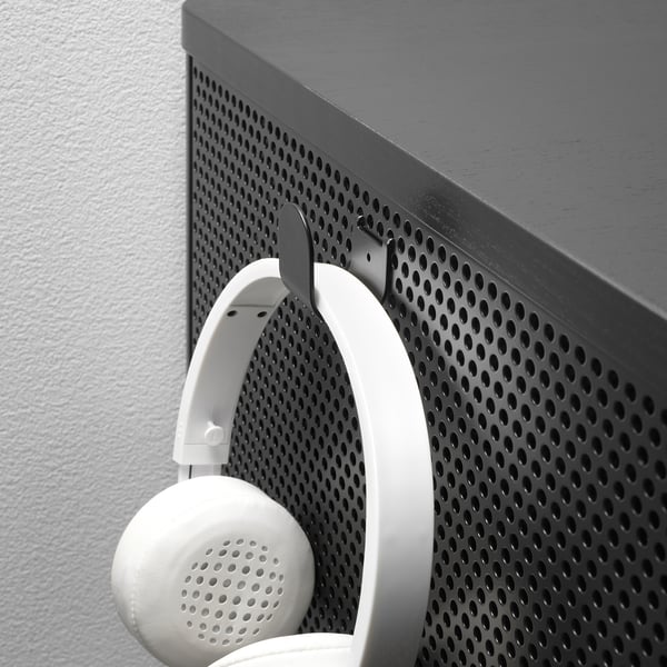 White headphones hang on metal mesh wall-mounted shelf.