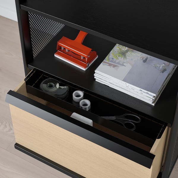 Black office storage unit on wheels with open drawer showing scissors, tape, and binding tools. Lock and cord management visible.
