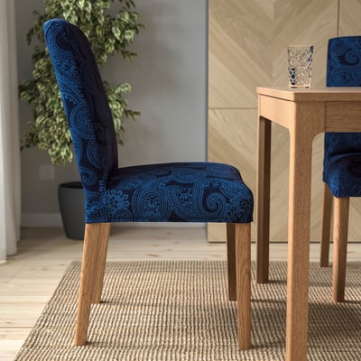 Patterned chair by table for dining, with wooden legs, comfortable cushioning, adjustable back support, and removable, washable cover.