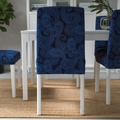 Three chairs with blue paisley-patterned covers are arranged around a dining table, providing a comfortable and stylish seating option.
