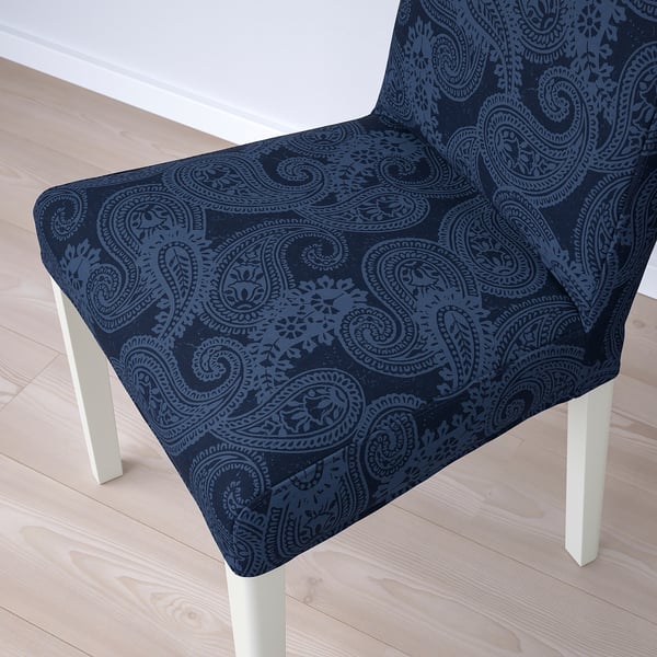 Dark blue paisley-patterned chair cover on a white chair with wooden legs, shown on a light wooden floor.