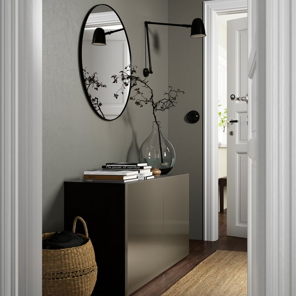 Modern living room with BESTÅ grey sideboard, mirror, vase, books, wall lamps, and basket.